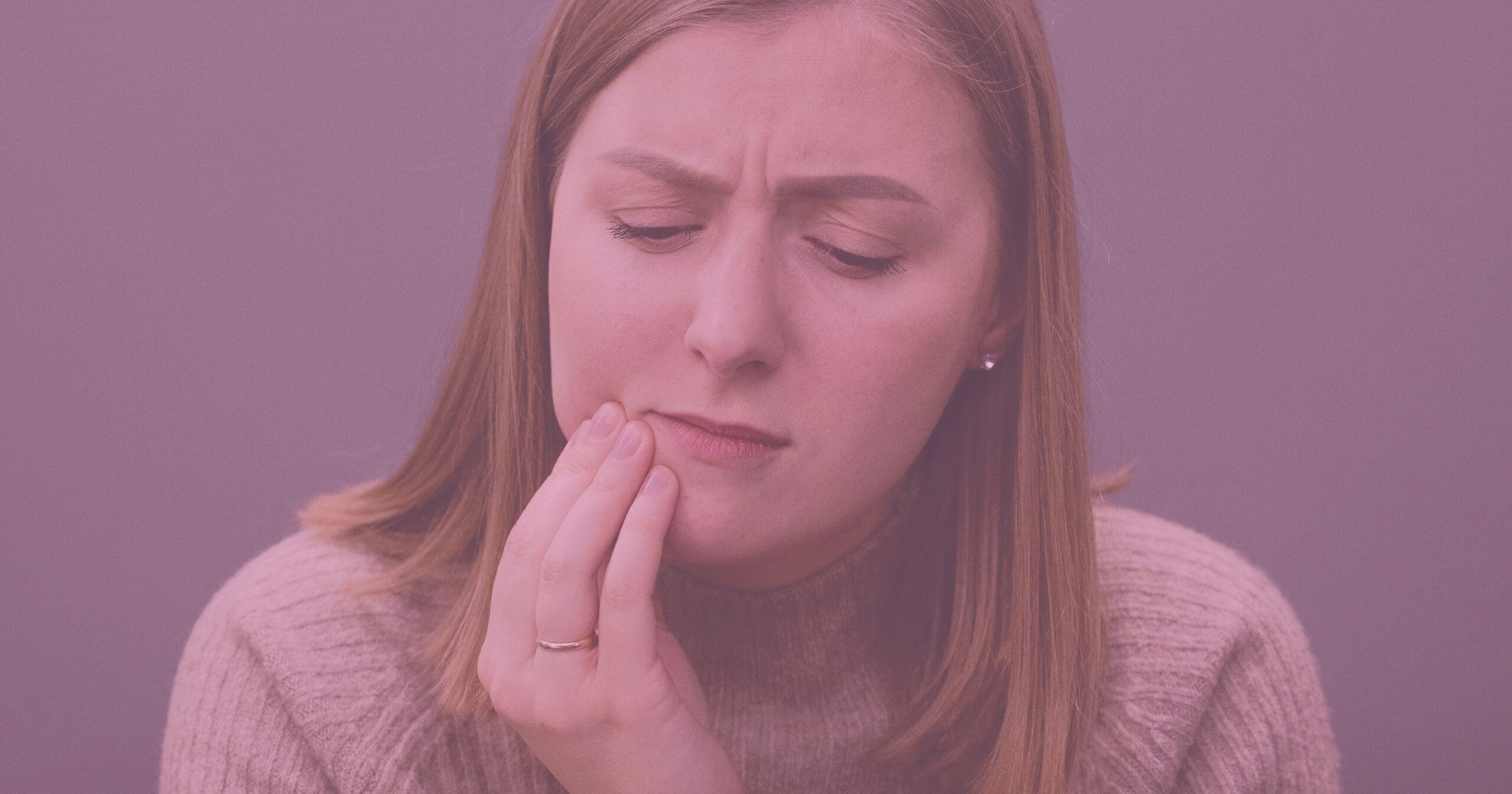 an image of a woman holding her jaw in pain with a pink overlay